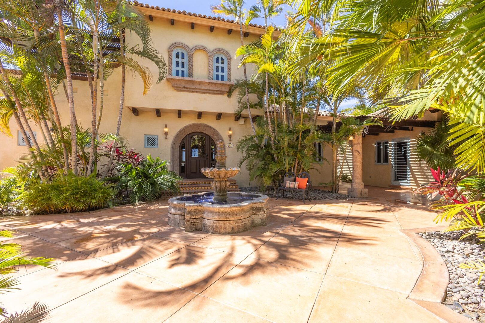 Front entrance with tiled fountain and palm-shaded facade